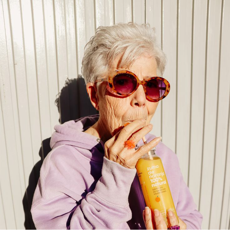 Mujer con lentes de sol apoyada en una pared